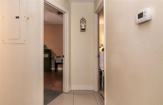 corridor featuring electric panel, visible vents, baseboards, and light tile patterned floors