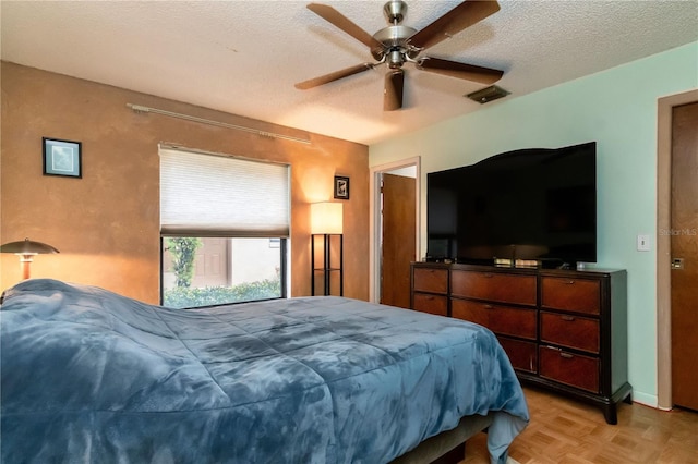 bedroom featuring visible vents, a textured ceiling, and a ceiling fan