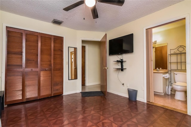 unfurnished bedroom with visible vents, a textured ceiling, ensuite bath, a closet, and baseboards