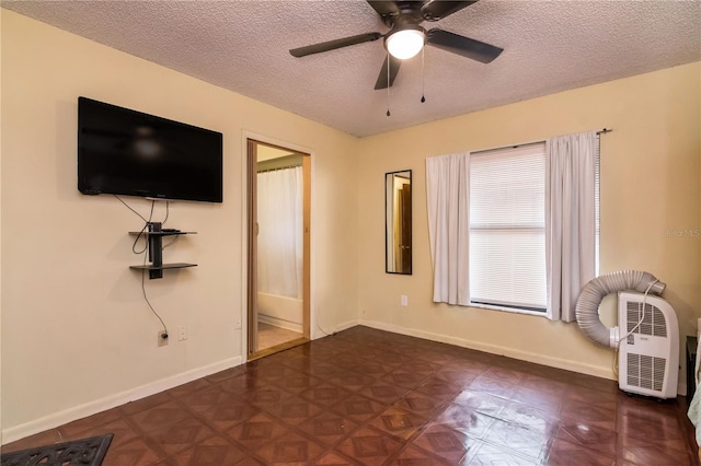 unfurnished bedroom with ceiling fan, baseboards, and a textured ceiling