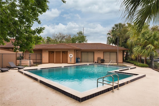 community pool with a patio area and fence