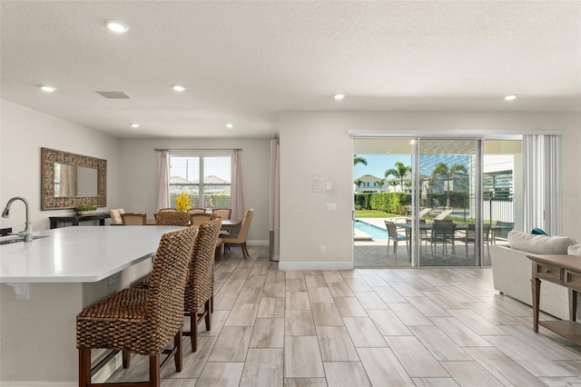 interior space with baseboards, visible vents, light wood-style flooring, recessed lighting, and a textured ceiling