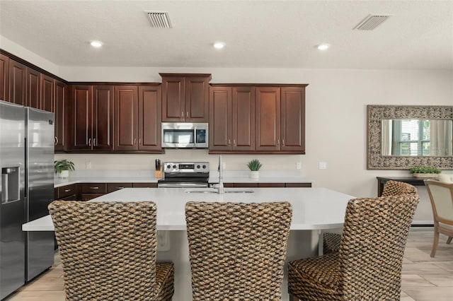 kitchen with a kitchen breakfast bar, visible vents, and appliances with stainless steel finishes