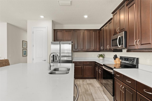 kitchen with visible vents, a sink, a textured ceiling, appliances with stainless steel finishes, and light countertops