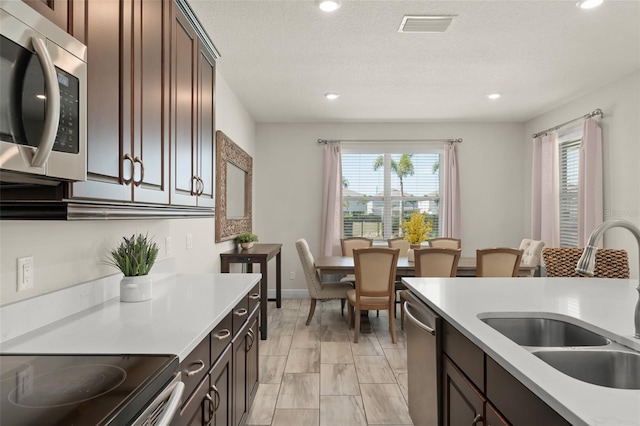 kitchen with visible vents, a sink, appliances with stainless steel finishes, light countertops, and a healthy amount of sunlight