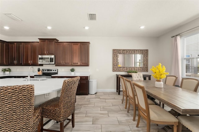 kitchen with visible vents, dark brown cabinets, stainless steel appliances, and a sink