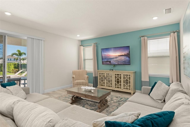 living room with wood finished floors, baseboards, visible vents, and a wealth of natural light