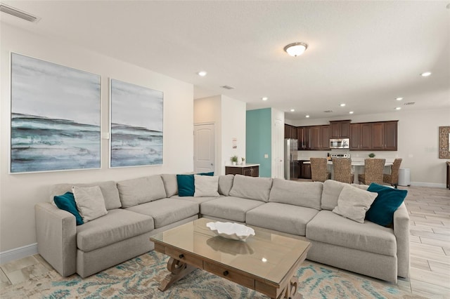 living area with light wood-style flooring, recessed lighting, visible vents, and baseboards