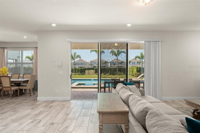 living room featuring baseboards, plenty of natural light, and a textured ceiling