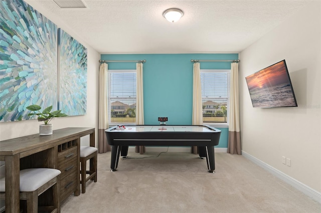 recreation room with plenty of natural light, light colored carpet, baseboards, and a textured ceiling