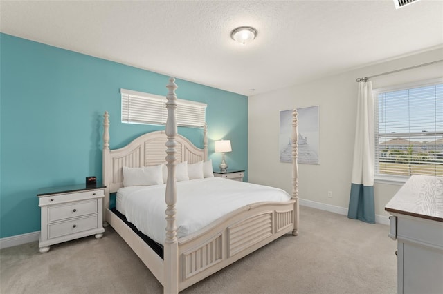 bedroom with baseboards, light carpet, and a textured ceiling