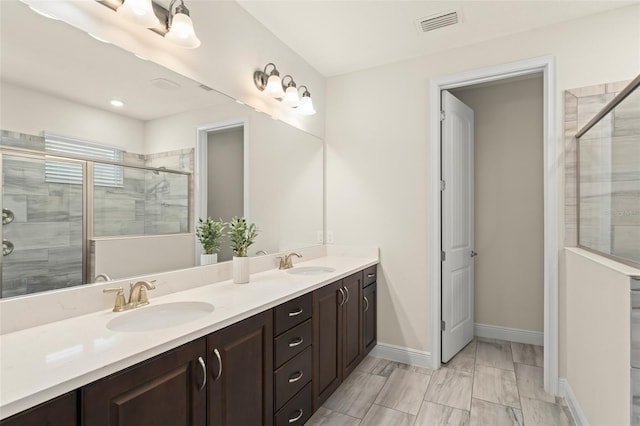 full bath with a sink, visible vents, a stall shower, and double vanity