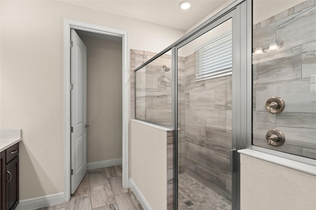 full bath featuring baseboards, vanity, and a shower stall