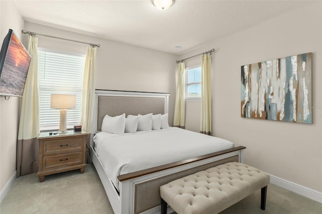 bedroom with light colored carpet, baseboards, and a textured ceiling