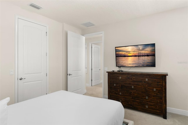 bedroom with light carpet, visible vents, a textured ceiling, and baseboards