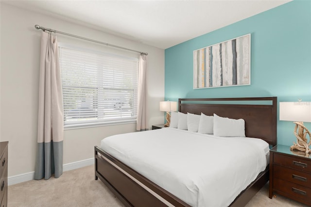 bedroom with light colored carpet and baseboards