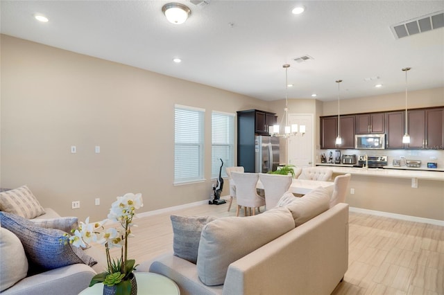 living area with light wood finished floors, baseboards, visible vents, and recessed lighting