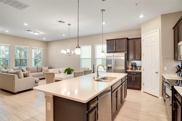 kitchen with appliances with stainless steel finishes, light countertops, a sink, and dark brown cabinetry