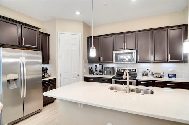 kitchen featuring stainless steel appliances, dark brown cabinets, a sink, and light countertops