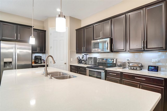 kitchen with appliances with stainless steel finishes, a sink, dark brown cabinetry, and tasteful backsplash