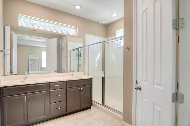 full bathroom featuring double vanity, a stall shower, tile patterned flooring, and a sink