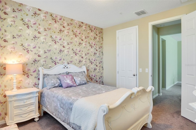 bedroom with carpet, visible vents, a textured ceiling, baseboards, and wallpapered walls