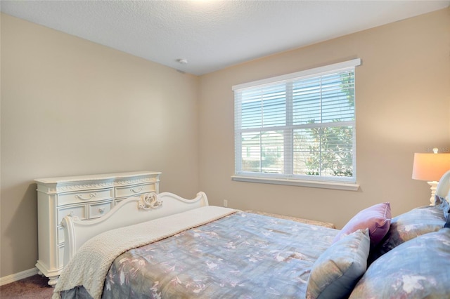 bedroom with carpet, baseboards, and a textured ceiling