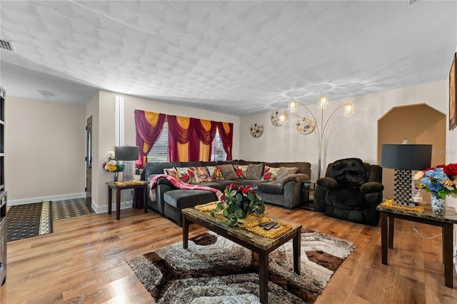 living room with visible vents, baseboards, and wood finished floors