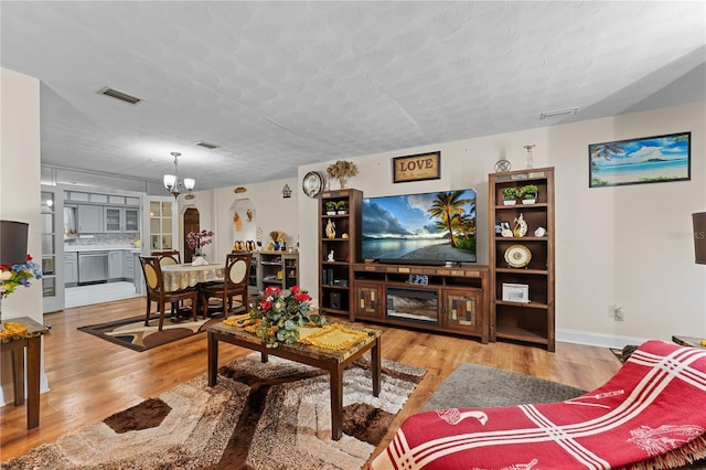 living area featuring visible vents, a textured ceiling, an inviting chandelier, and wood finished floors