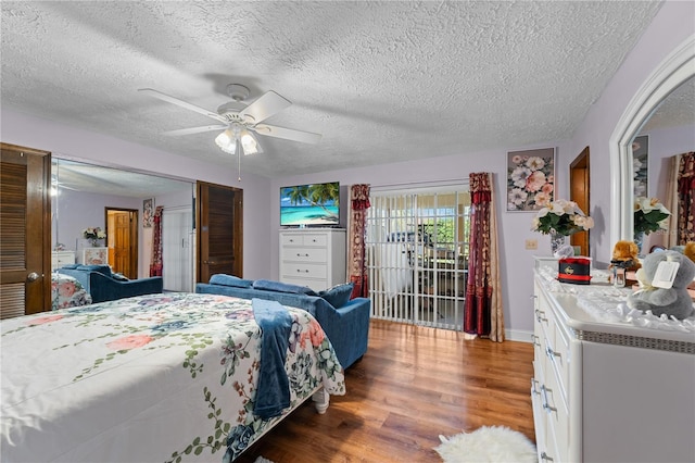 bedroom with a ceiling fan, access to exterior, wood finished floors, and a textured ceiling