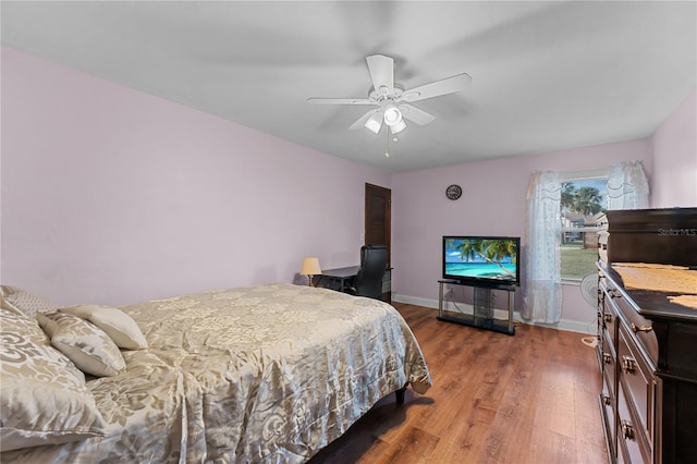 bedroom with a ceiling fan, wood finished floors, and baseboards