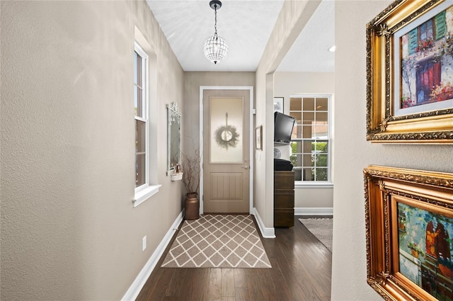 doorway featuring baseboards, an inviting chandelier, and dark wood-style floors