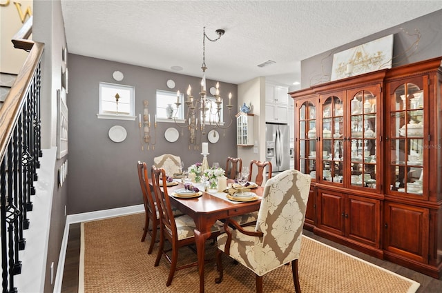 dining room featuring visible vents, a textured ceiling, a chandelier, and stairs