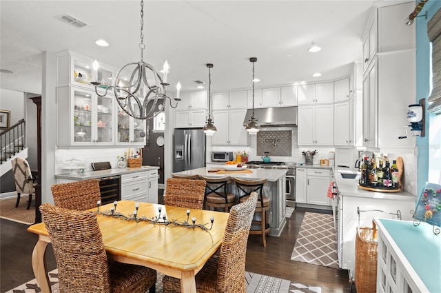 kitchen featuring visible vents, a sink, stainless steel appliances, wine cooler, and under cabinet range hood