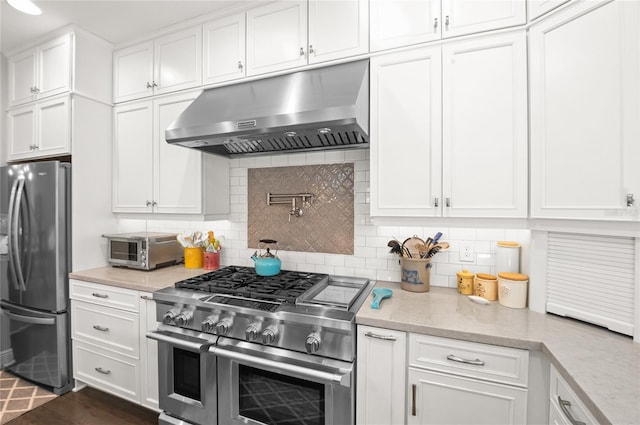 kitchen with under cabinet range hood, stainless steel appliances, backsplash, and white cabinetry