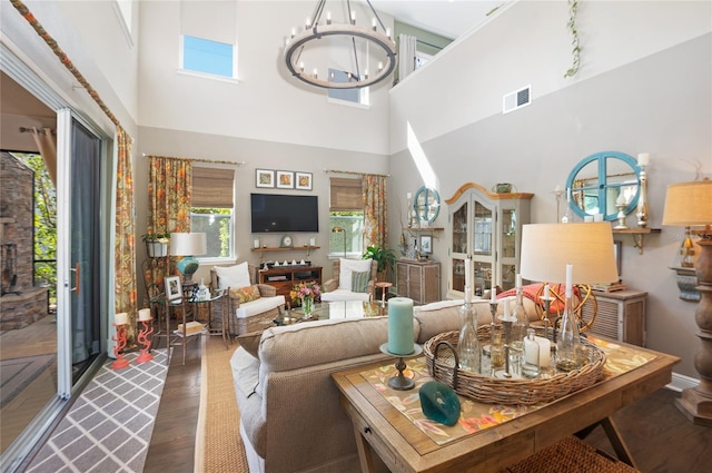 living area featuring visible vents, wood finished floors, a fireplace, a chandelier, and a towering ceiling