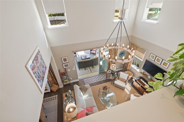 living room with a notable chandelier, a high ceiling, and wood finished floors