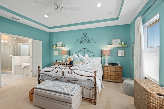 carpeted bedroom featuring a ceiling fan, visible vents, a tray ceiling, ensuite bathroom, and crown molding