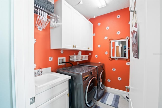 washroom featuring cabinet space, independent washer and dryer, baseboards, and a sink