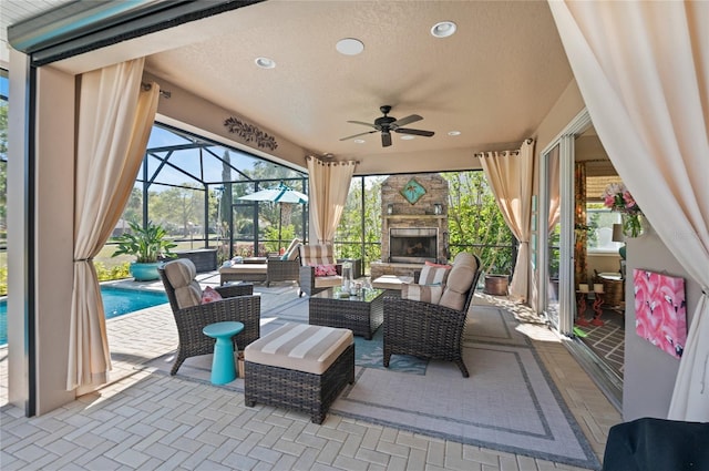 view of patio / terrace featuring a lanai, an outdoor living space with a fireplace, an outdoor pool, and ceiling fan