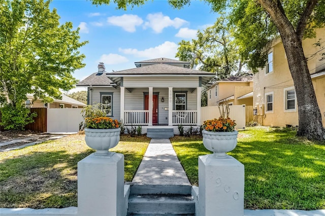 bungalow-style house with a chimney, covered porch, a front yard, and fence