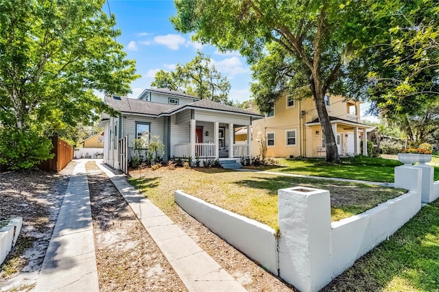 bungalow with a porch, fence, and a front lawn