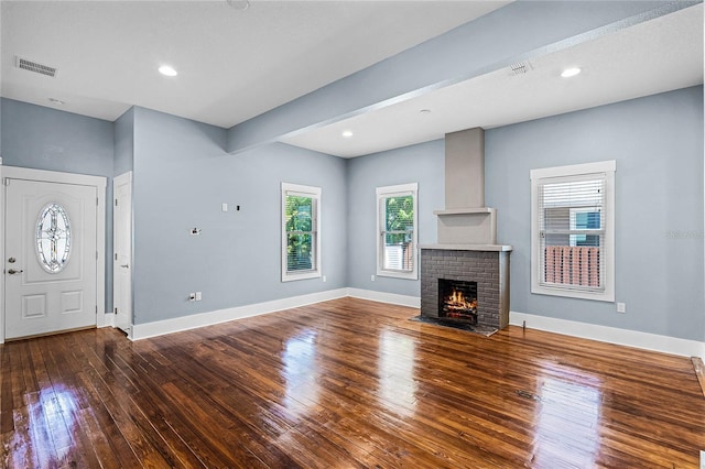 unfurnished living room featuring visible vents, baseboards, hardwood / wood-style floors, and a fireplace