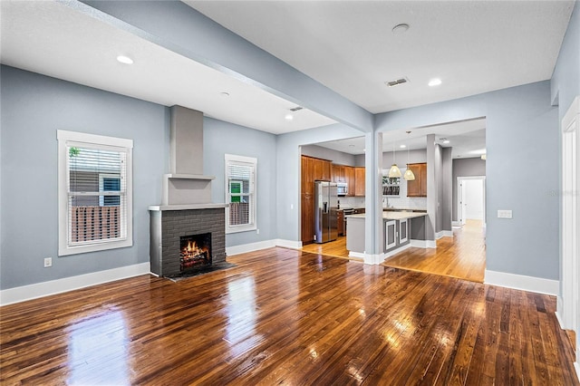 unfurnished living room with light wood finished floors, plenty of natural light, a fireplace, and baseboards