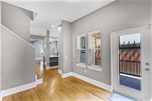 foyer with light wood finished floors, stairway, and baseboards