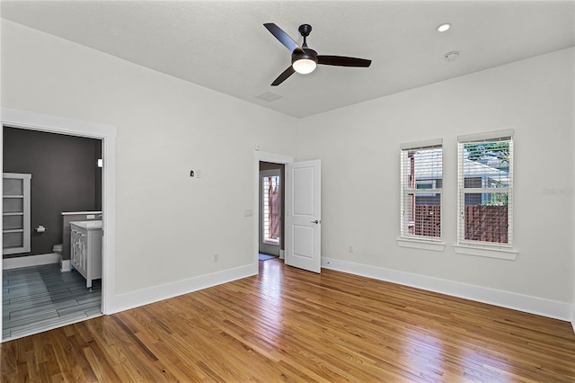 unfurnished bedroom with visible vents, baseboards, light wood finished floors, and connected bathroom