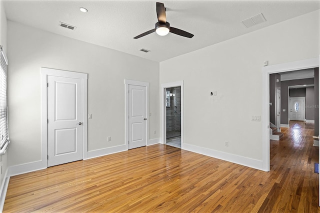 unfurnished bedroom featuring visible vents, light wood-style flooring, ensuite bathroom, and baseboards