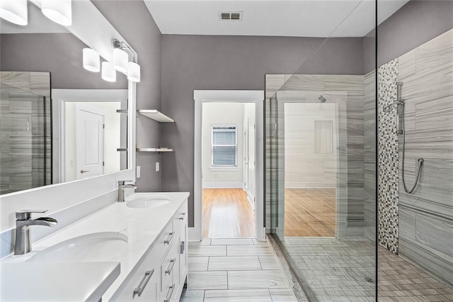 full bathroom featuring a sink, visible vents, a stall shower, and double vanity