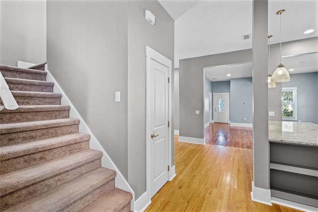 staircase featuring visible vents, baseboards, and wood finished floors