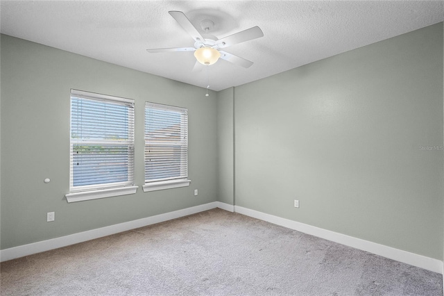 carpeted spare room featuring a textured ceiling, baseboards, and a ceiling fan